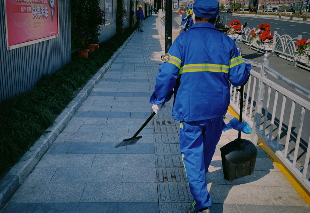 a man in a blue coverall walking down a sidewalk